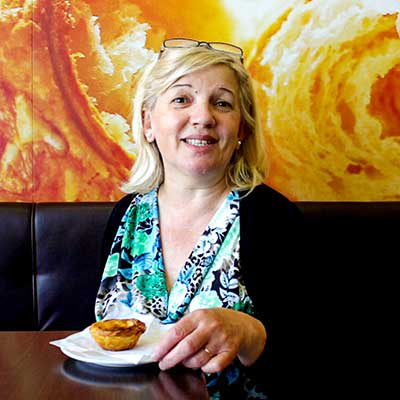 Cliente da Pastelaria Patyanne a segurar um pastel de nata à mesa