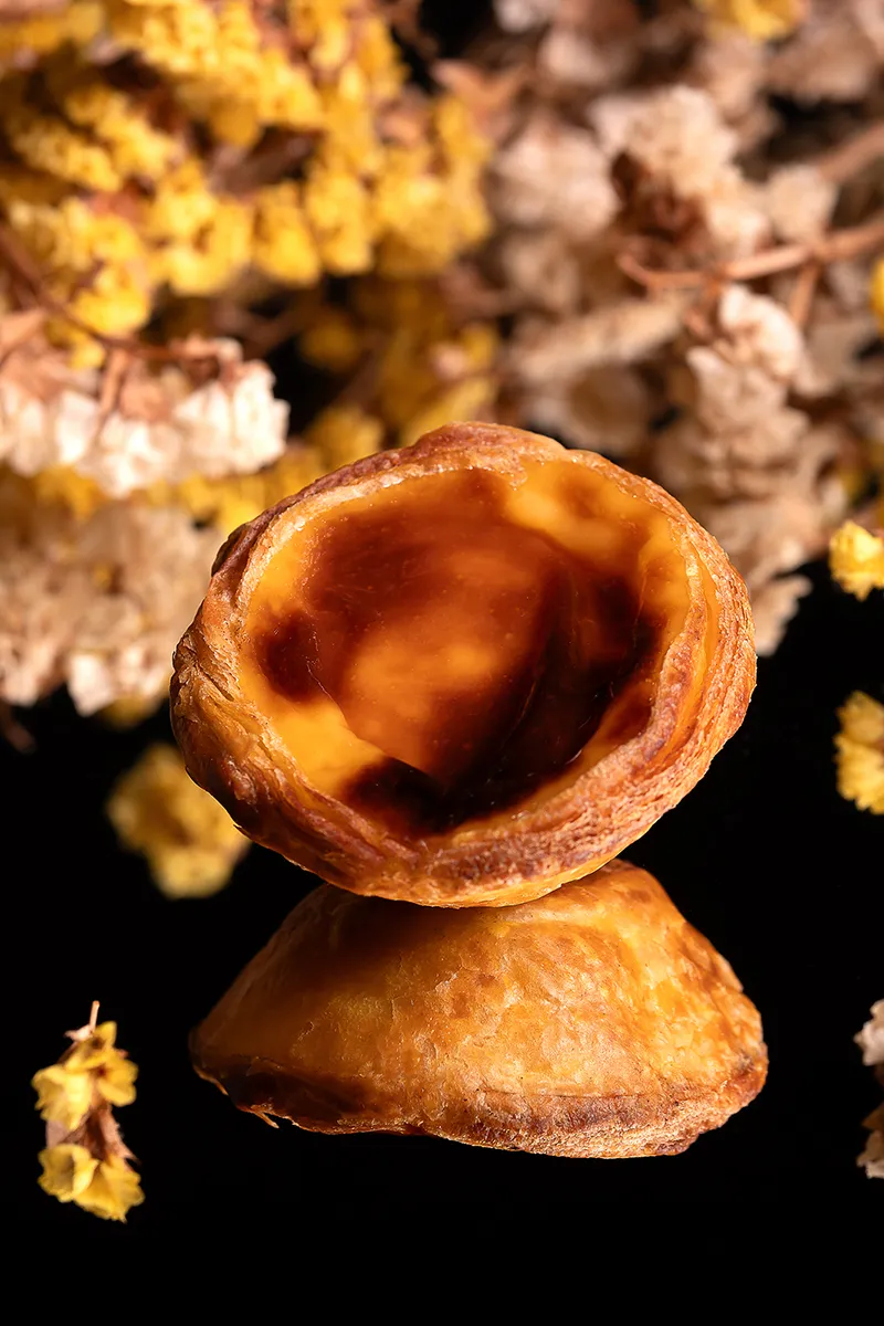 Pastel de nata artesanal da Pastelaria Patyanne com moinho de café e grãos sobre fundo claro